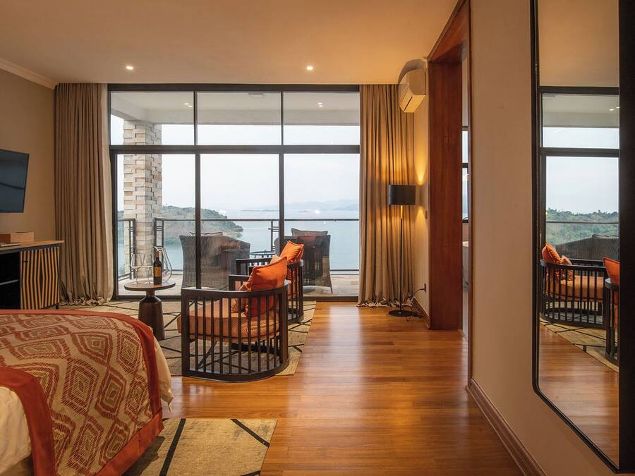 Habitación de hotel con cama, televisión, balcón y vista al mar, además de un ventanal grande.