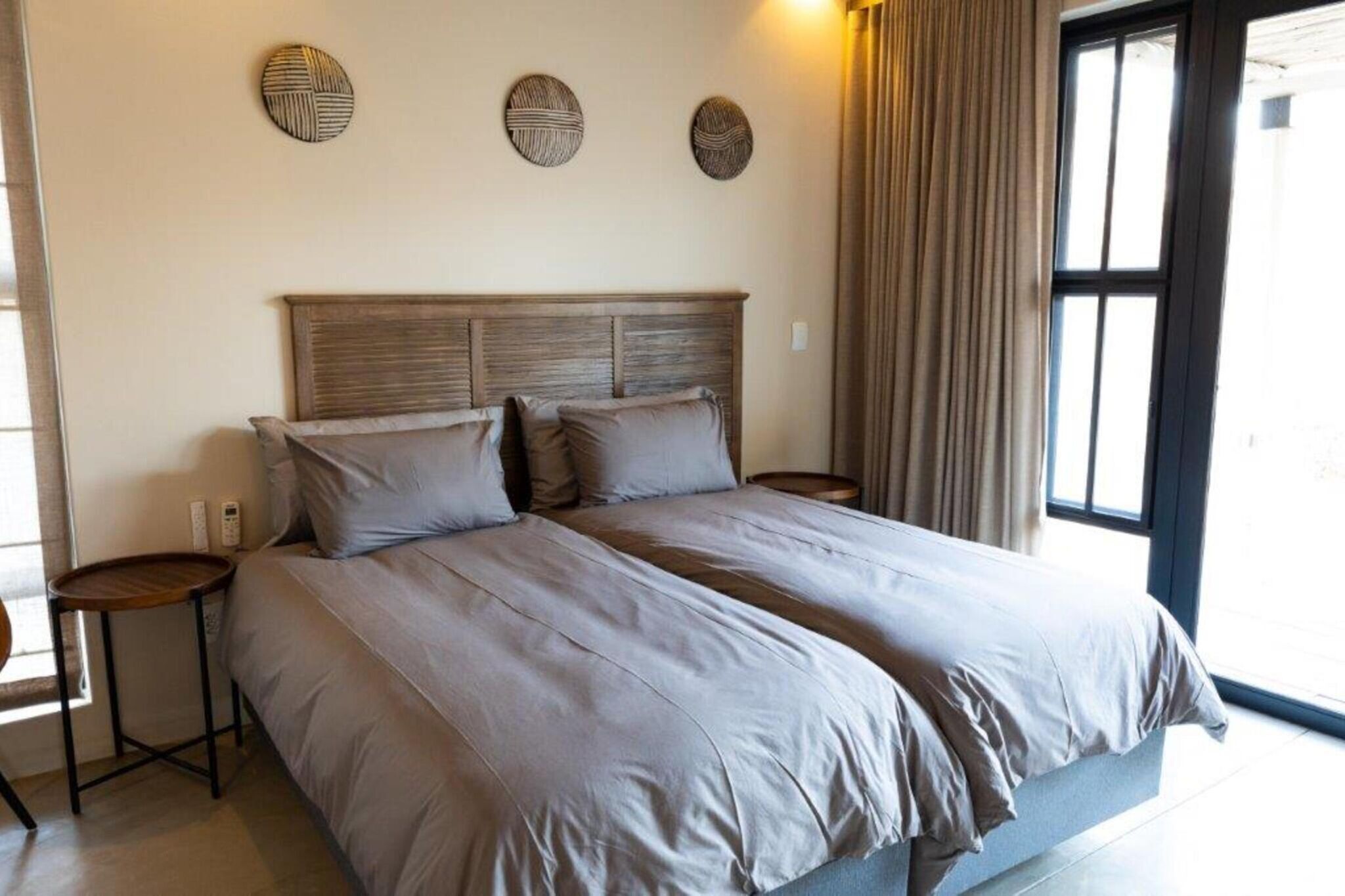 A double bed with a wooden headboard, two bedside tables, and three wall-mounted decorative items.