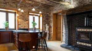 A kitchen with a brick wall, wooden bar stools, a large window, and a black stove. - Villa with swimming pool in Erembodegem (Erembodegem)