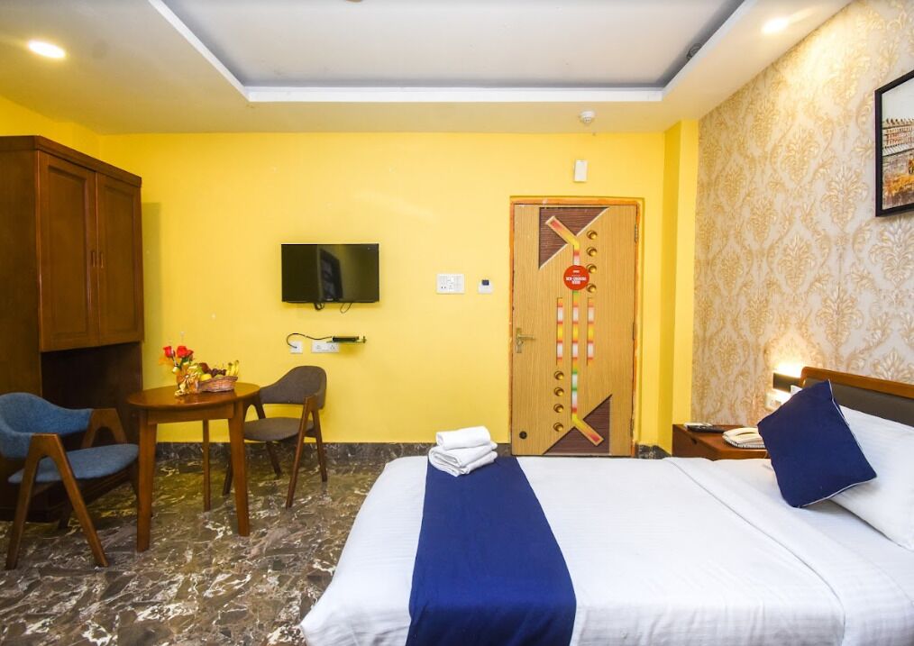 A hotel room with a bed, a desk, a chair, a television, and a door with a decorative design.