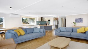 A modern living room with two blue sofas, a wooden coffee table, and a dining area with a table and chairs. - Bella Vista Valley Views (BLACKHEATH)
