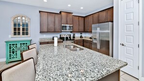 A kitchen with granite countertops, stainless steel appliances, wooden cabinets, and a teal cabinet. - Elegant Home near Disney: Private Pool & Waterpark & Resort - 7610WI (Kissimmee)