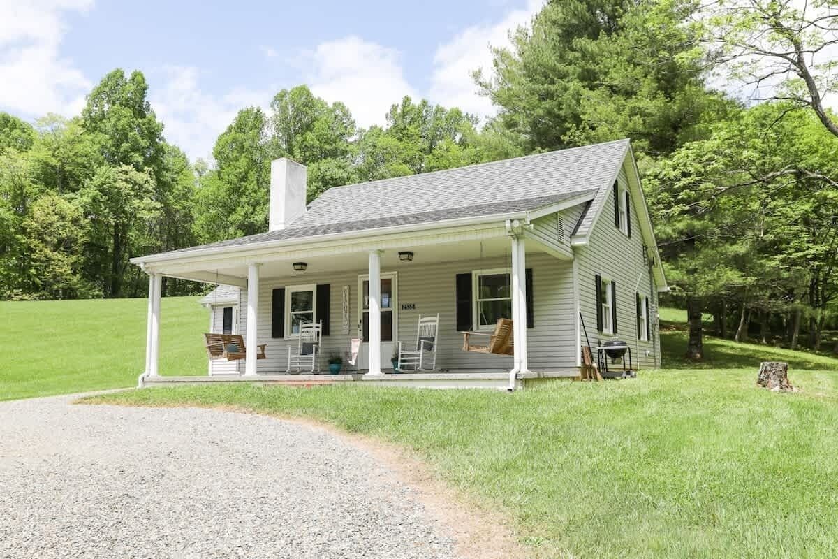A single-story house with a porch, a chimney, and a gravel driveway.
