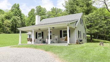 A single-story house with a porch, a chimney, and a gravel driveway.
