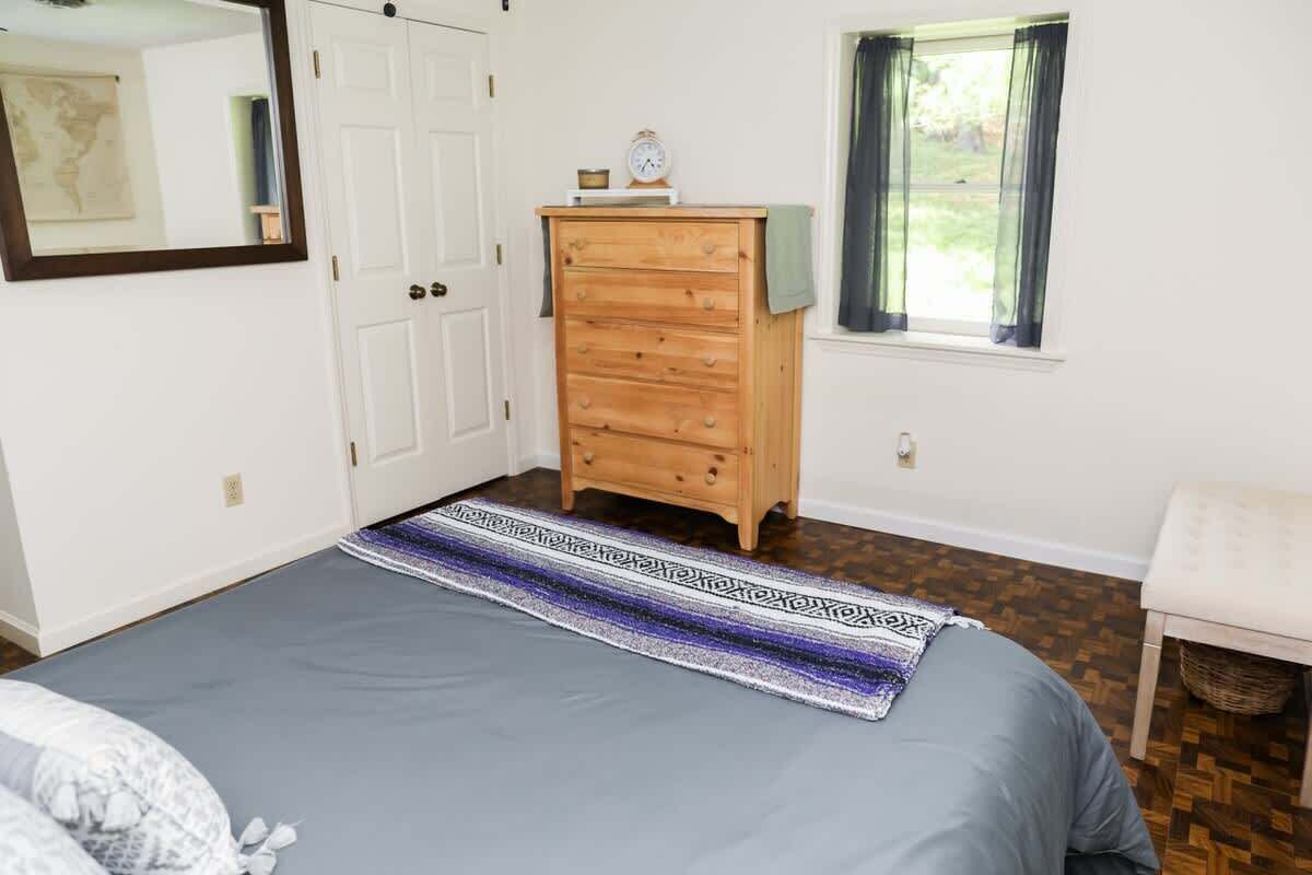 A bedroom with a bed, dresser, window, and a map on the wall.