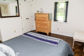 A bedroom with a bed, dresser, window, and a map on the wall.