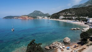 A coastal town with clear waters, a beach, and rocky outcrops. - Hotel G Star (Sutomore)