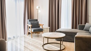 A modern living room with a grey sofa, a round coffee table, a wooden armchair, and a floor lamp. - Hotel G Star (Sutomore)