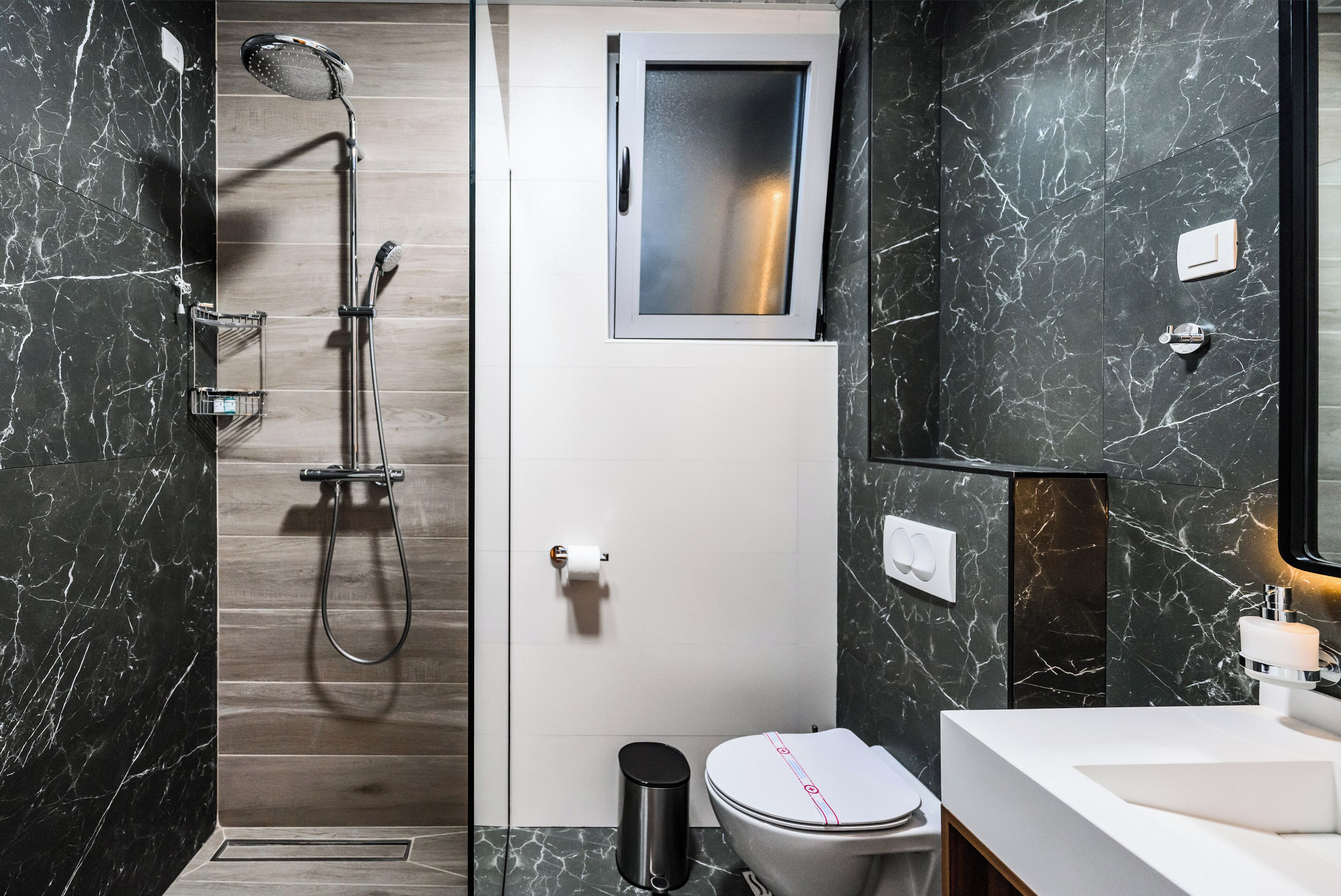 A modern bathroom with a shower, toilet, and sink.