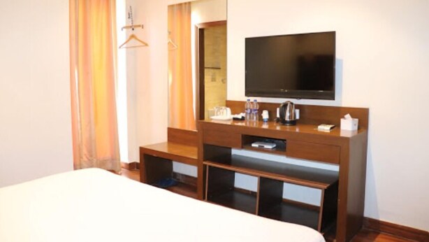 Ein Hotelzimmer mit einem Bett, einem Holztisch mit Flachbildfernseher, einem Spiegel und einer kleinen Sitzecke.
