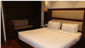 Ein Hotelzimmer mit einem großen Bett, einem Nachttisch, einer Lampe und einer Sitzecke.