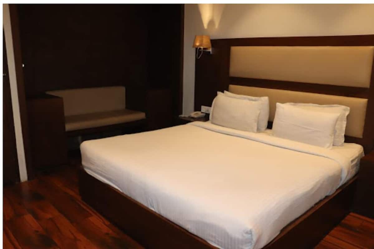 Habitación de hotel con una cama grande, una mesita de noche, una lámpara y una zona de estar.