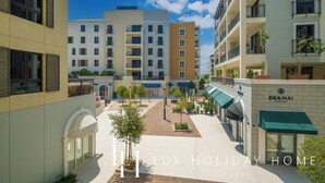 A modern hotel with multiple floors, outdoor seating areas, and a clear sky.