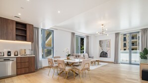 A spacious living area with a dining table, sofas, and a kitchen area with modern appliances.