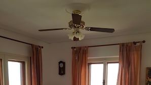 A dining area with a table, chairs, a ceiling fan, and a clock on the wall.