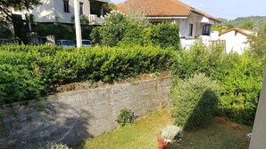 A residential area with a grassy yard, a stone wall, and a building with a tiled roof.