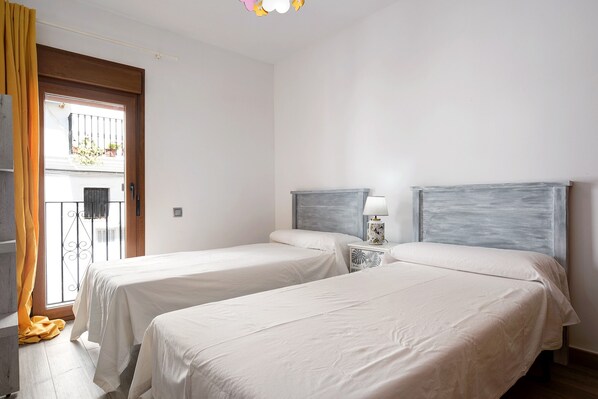 A room with two beds, a window with a view, and a door.