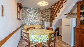 Un espace repas comprenant une table, des chaises, un canapé, un réfrigérateur et un escalier.