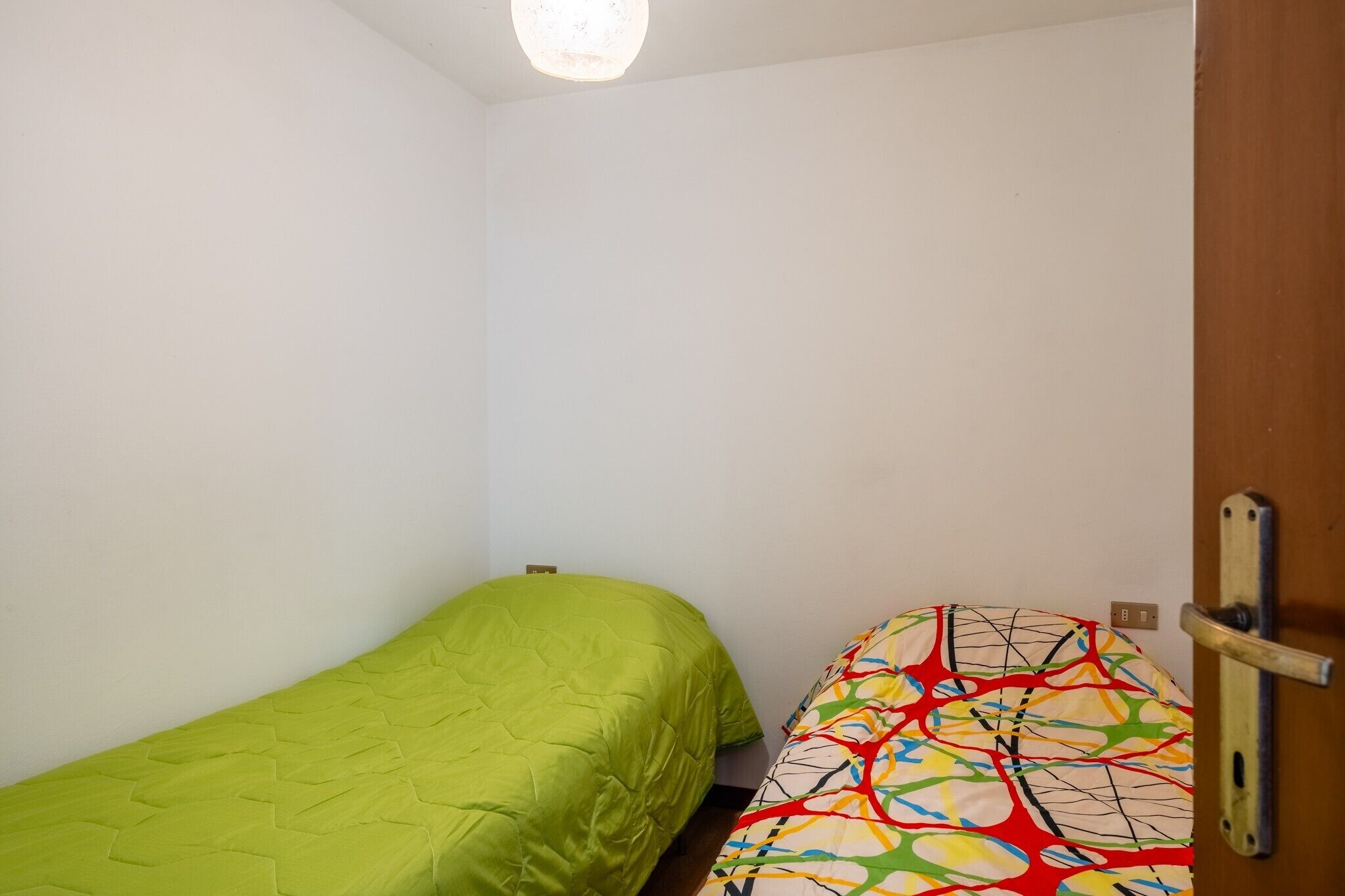 Une petite pièce avec un lit à gauche et une chaise à droite.