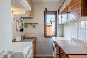 Cocina compacta con lavadora, lavamanos y armarios de madera.