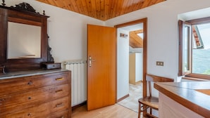 Une pièce avec un plafond en bois, une commode en bois, une chaise en bois, une porte en bois et une fenêtre donnant sur un beau paysage.