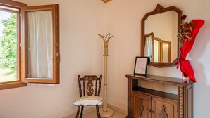 A room with a wooden chair, a tall floor lamp, a mirror, and a wooden cabinet.