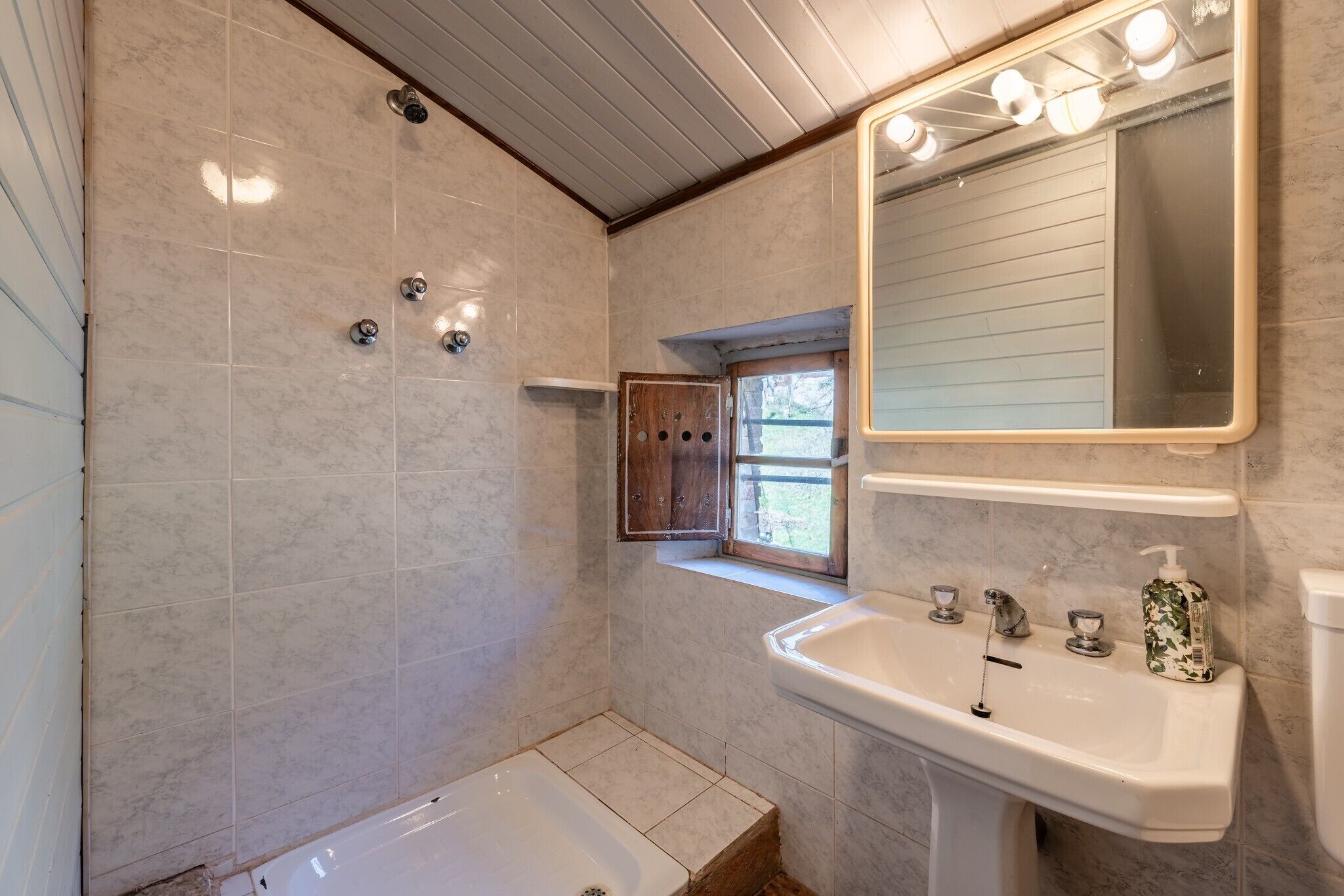 A bathroom with a bathtub, a sink, a mirror, and a window.