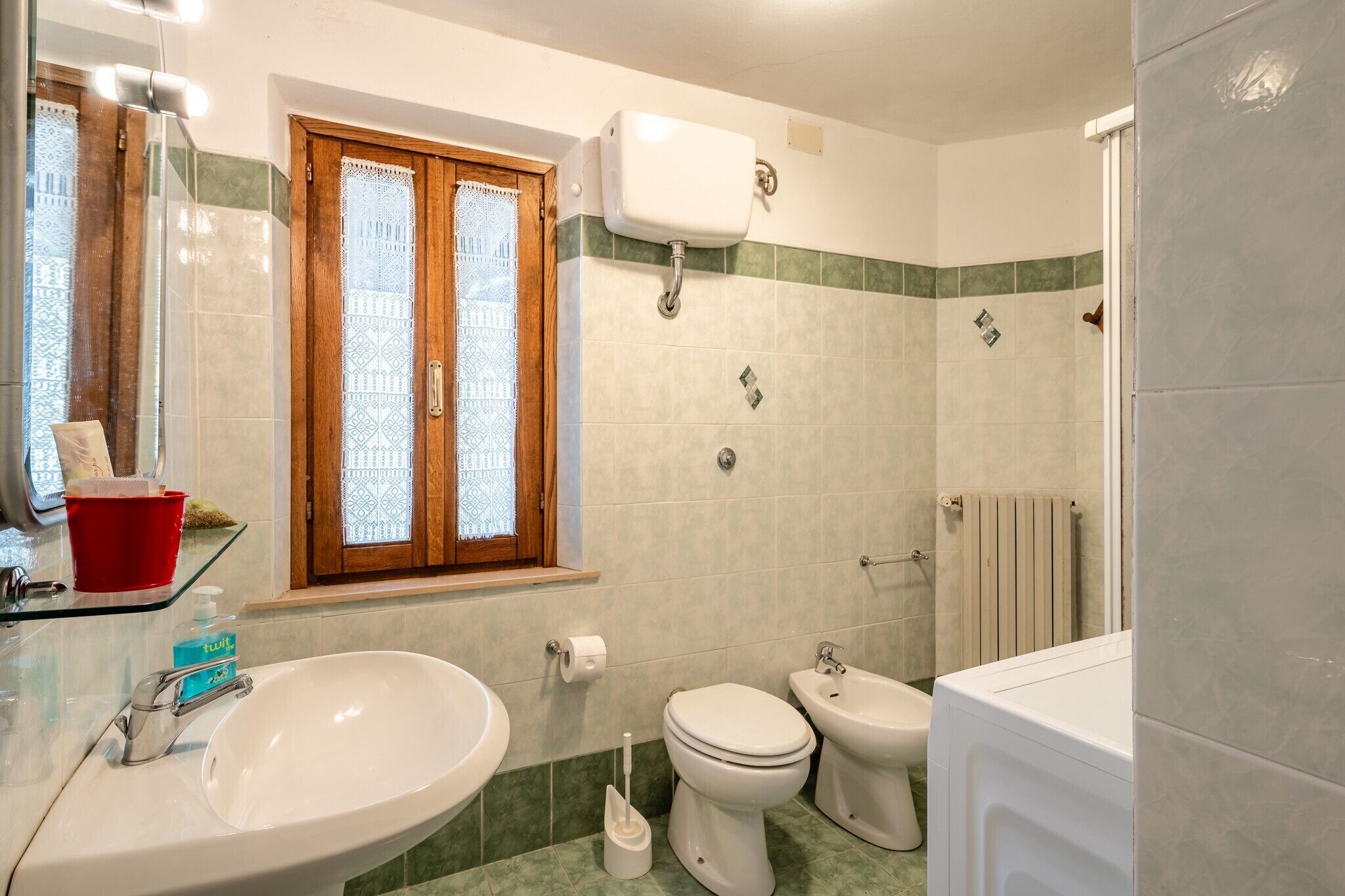 Et badeværelse med vask, toilet, bidet og bruseområde.