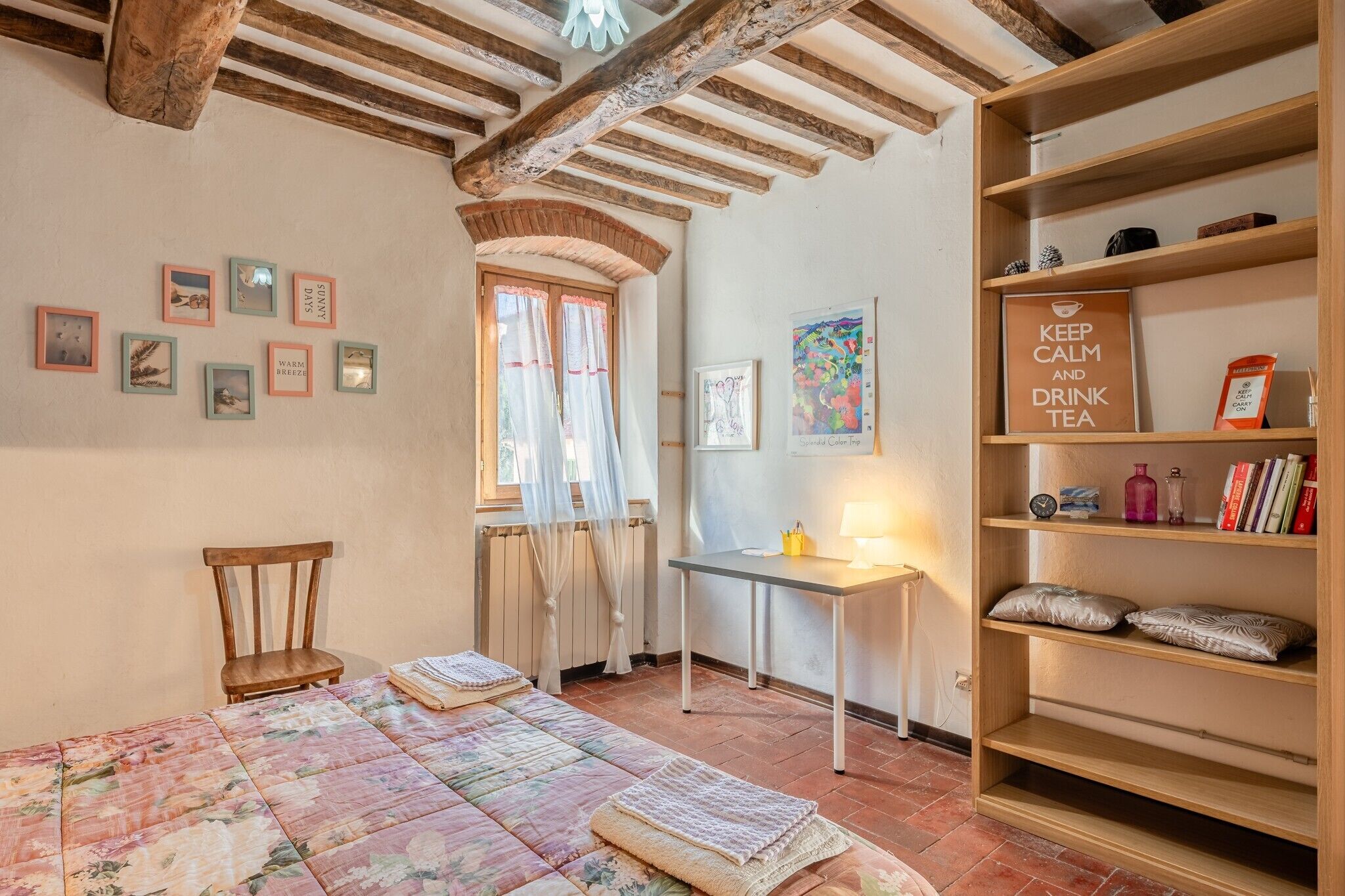 Una camera accogliente con un letto, una sedia, un tavolo e una libreria.