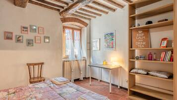 Una camera accogliente con un letto, una sedia, un tavolo e una libreria.