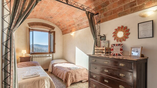 Een kamer met twee bedden, een kapstok, een raam met uitzicht en een plafond van baksteen.