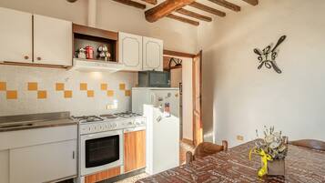 A kitchen with a stove, oven, microwave, and refrigerator. There is a dining table with a yellow ribbon and a bouquet of flowers.