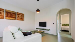 A modern living room with a white sofa, a flat-screen TV, and three abstract paintings on the wall. - Holiday Home 'Carpa' with Mountain View, Wi-Fi and Air Conditioning (Riumar)