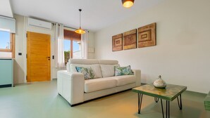 A living room with a white sofa, a small table, and a wooden door. - Holiday Home 'Carpa' with Mountain View, Wi-Fi and Air Conditioning (Riumar)