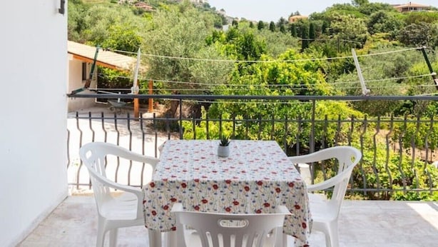 A balcony with a table and chairs, a view of greenery and buildings, and a metal railing. - Villa 'Lucia' with Shared Terrace and Wi-Fi (Minturno)
