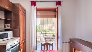 A room with a dining table, chairs, a microwave, oven, and a view of a balcony with a table and chairs. - Villa 'Lucia' with Shared Terrace and Wi-Fi (Minturno)