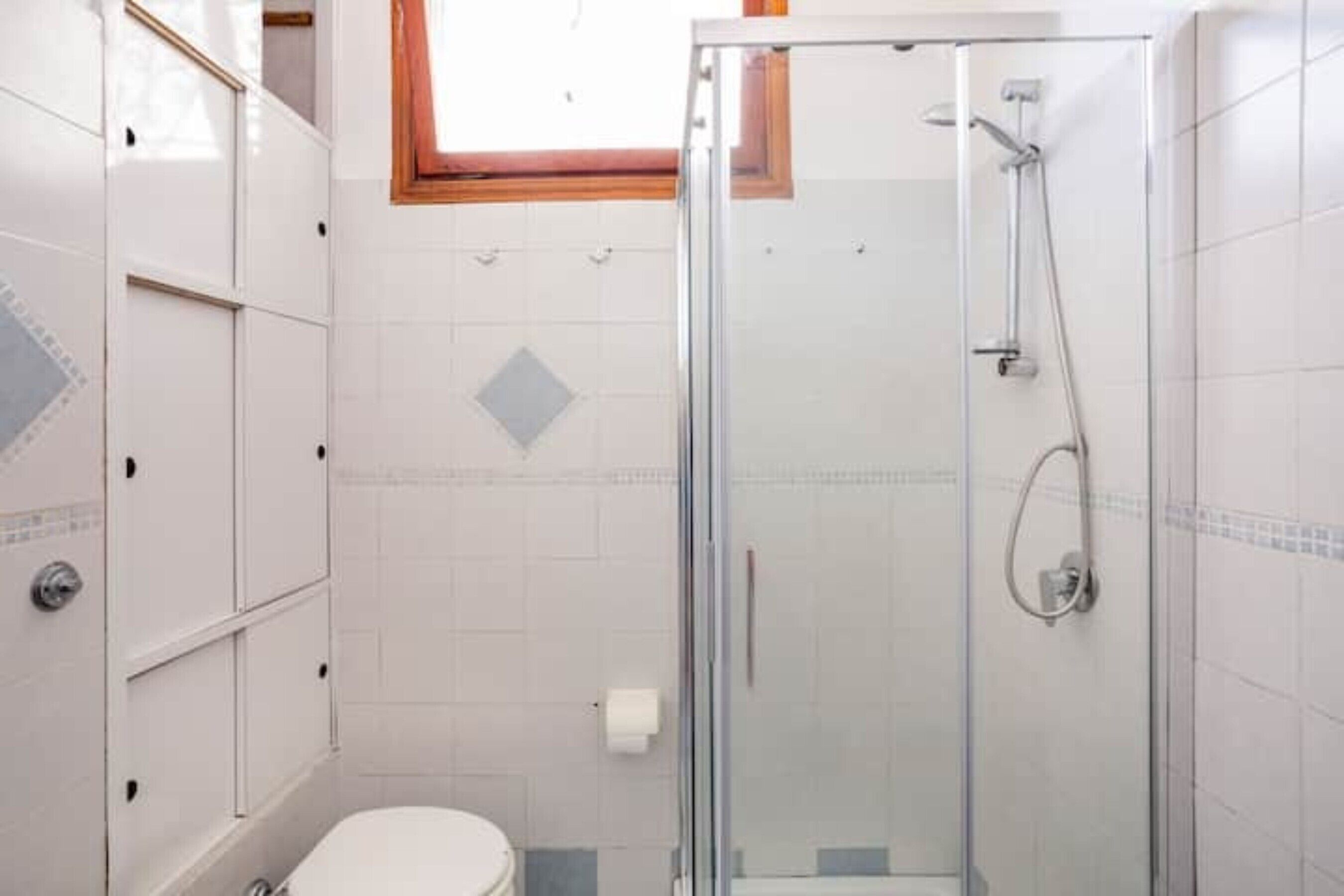 Ein Badezimmer mit Duschkabine, Toilette und Fliesenwänden.