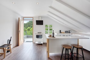 Une cuisine moderne dotée d’un grand îlot central, d’appareils électroménagers intégrés et offrant une vue sur la verdure.