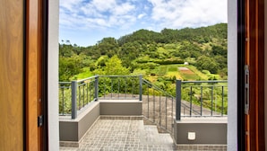 A balcony with a view of a lush green landscape and a clear sky.