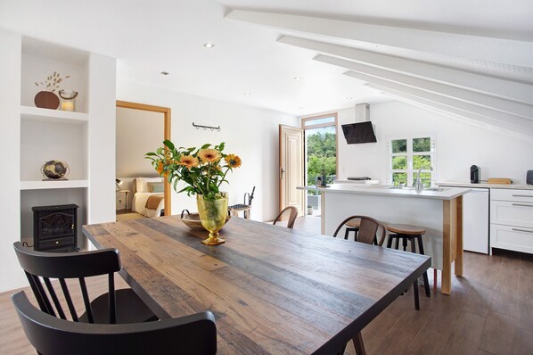 Une cuisine moderne avec un îlot central en bois, des meubles blancs et une grande fenêtre.
