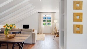 A modern living room with a dining area, a sofa set, a TV, and a window with curtains.