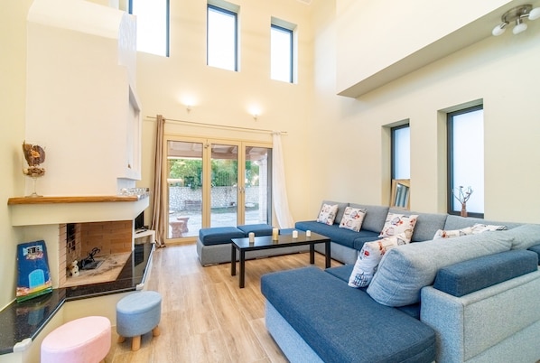 A spacious living area with a sofa, ottoman, and fireplace.