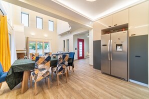 A modern kitchen with a built-in refrigerator, wooden flooring, and a dining area with a table and chairs.