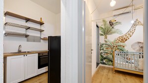 Eine Küche mit weißen Schränken, einem schwarzen Kühlschrank und Holzregalen.