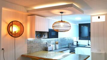 Une cuisine moderne dotée d’un îlot central, de luminaires suspendus et d’un coin repas avec des chaises.