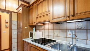 Een keuken met houten kastjes, een magnetron, een fornuis en een spoelbak.