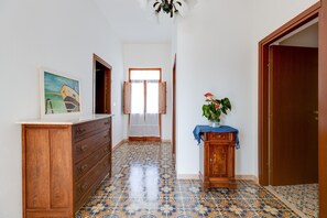 A hallway with patterned floor tiles, wooden cabinets, a painting, and a potted plant. - Holiday Home 'Da Flavia' with Private Terrace, Private Garden and Air Conditioning (riola sardo)
