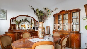 A dining room with a round table, chairs, a decorative vase, and a wooden cabinet with glass doors. - Holiday Home 'Da Flavia' with Private Terrace, Private Garden and Air Conditioning (riola sardo)