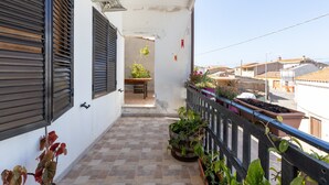 A balcony with potted plants, a small table, and a view of neighboring buildings. - Holiday Home 'Da Flavia' with Private Terrace, Private Garden and Air Conditioning (riola sardo)