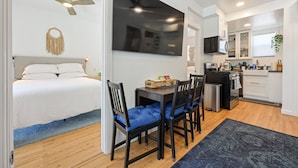 A modern hotel room with a bed, a desk with chairs, a kitchenette, and a large TV. - Hot Tub/1mi to Downtown/3mi to Coronado/KING Bed/Wifi 300mb+/BBQgrill/Harborside (San Diego)